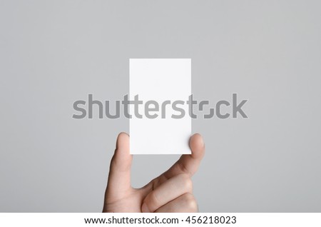 Business Card Mock-Up (85x55mm) - Male hands holding a blank card on a gray background.