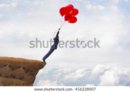 business freedom concept courageous daring businessman flying off a cliff holding faith in balloons Royalty-Free Stock Photo #456228007