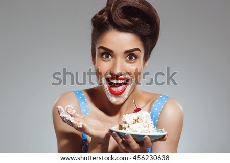 Picture of funny pin-up girl eating cake at studio