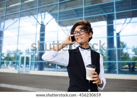 Young successful businesswoman speaking on phone, standing near business centre.
