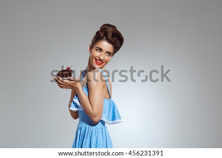 Picture of beautiful pin-up girl holding cake in hands at studio