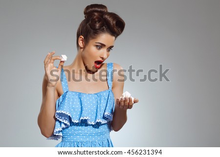 Picture of beautiful pin-up girl holding sweeties in hands at studio