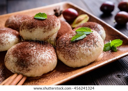 Traditional sweet steamed dumplings with a plum jam, sprinkled with a cocoa powder on a wooden plate and background