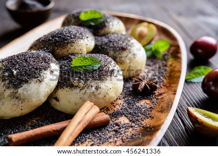 Traditional sweet steamed dumplings with a plum jam, sprinkled with ground poppy seeds on a wooden plate and background
 
