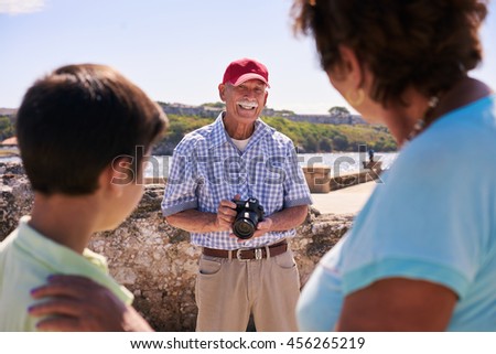 Happy tourists on holidays. Hispanic people traveling in Havana, Cuba. Grandfather, grandmother and grandchild during summer travel, with senior man taking photos with camera
