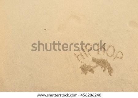 written words "HIP HOP" on sand of beach