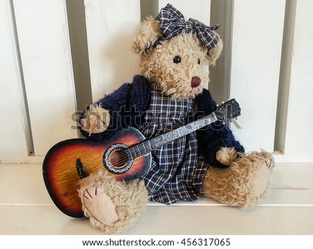 Teddy bear with guitar on wooden chair