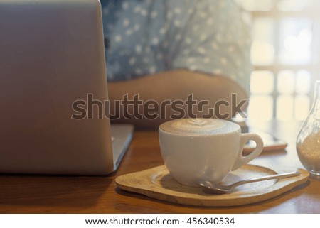 Business man sitting with glass of coffee in coffee shop interior. Attractive caucasian man eating and using notebook computer in cafe. Indoors