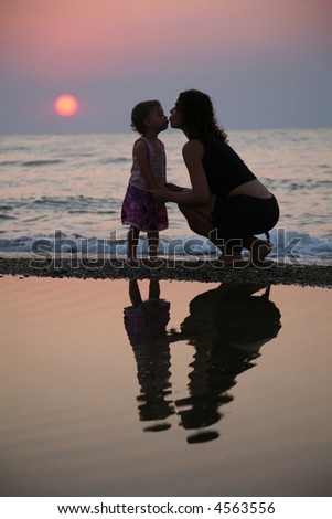 Mother with daughter ashore on sunset