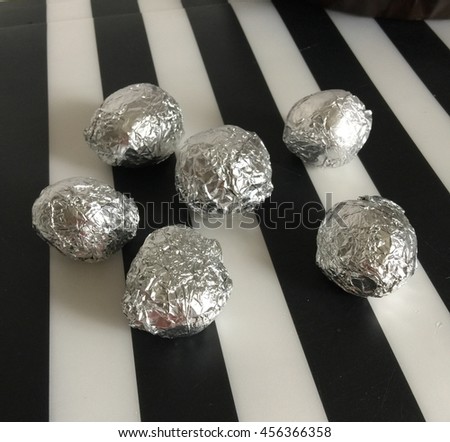 Potatoes in foil laying on table on black and white background. Food photography