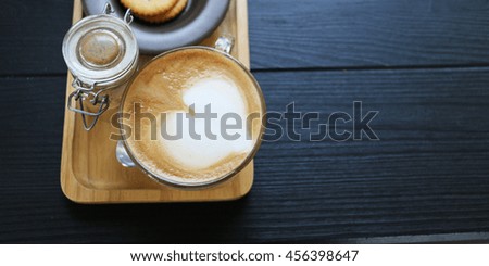 Coffee with heart shape foam on wooden tray