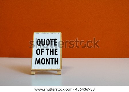 A Small cute wooden Sign or menu stand with orange background and word Quote of the month
