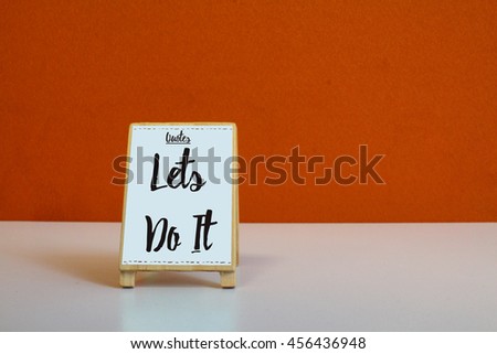 A Small cute wooden Sign or menu stand with orange background and word Quote Lets do it