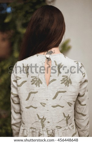A soft-focus image of girl's back in a dress. Small depth of field. Film grain effect.