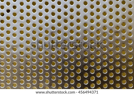 Metal stainless steel shiny flat grille with round holes and scratches on the surface.