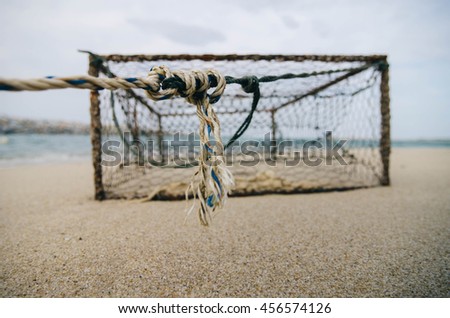 closeup and selective focus on rope over rusty crab pot on the sandy beach. 
