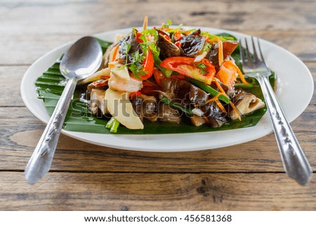 Partial and soft focus restaurant food - roasted potatoes with vegetables and mushrooms, parsley at light brown wooden background. 