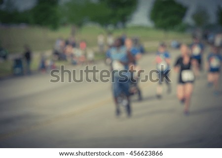 Blurred abstract motion group runners of all abilities of 10K race in Katy, Texas, US. Fitness and healthy lifestyle concept. Athletes on the race. Urban sport event. Vintage filter look.
