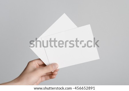 A6 Flyer / Postcard / Invitation Mock-Up - Male hands holding blank flyers on a gray background. Royalty-Free Stock Photo #456652891