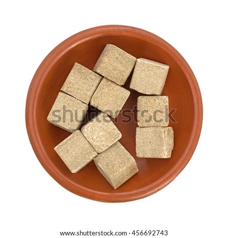 Top view of several beef flavored bouillon cubes filling a small bowl isolated on a white background.