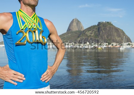 First place Brazilian athlete wearing gold 2016 medals standing outdoors in front of a view of Sugarloaf Mountain and Guanabara Bay from Botafogo Beach, Rio de Janeiro, Brazil 