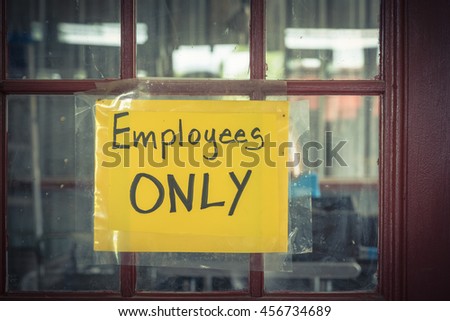 Handwriting Employee Only label with yellow plastic on rustic wooden door. Staff only, private access, restriction room concept. Vintage filter look.