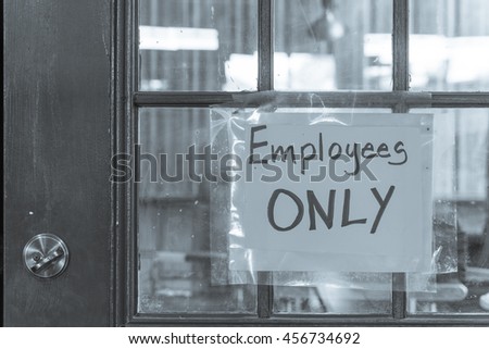 Handwriting Employee Only label with yellow plastic on rustic wooden door. Staff only, private access, restriction room concept. Black and white.