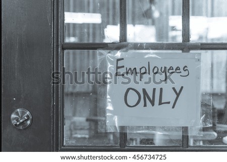Handwriting Employee Only label with yellow plastic on rustic wooden door. Staff only, private access, restriction room concept. Black and white.