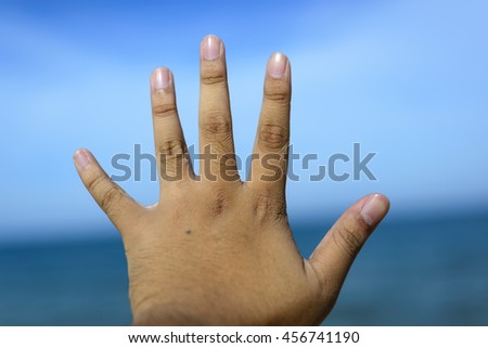 Male fingers showing number 5 isolated on bokeh blue-sea background. Copyspace is available.
