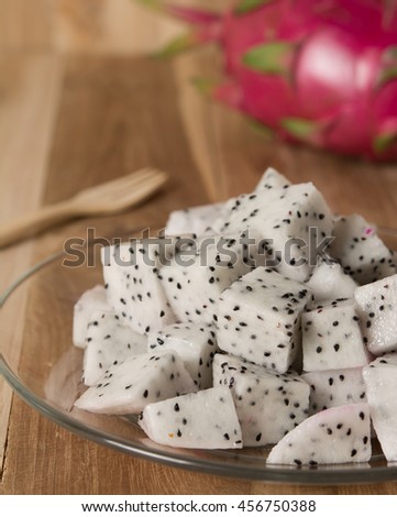 Pitahaya dragon fruit slices in white cup on wooden background.