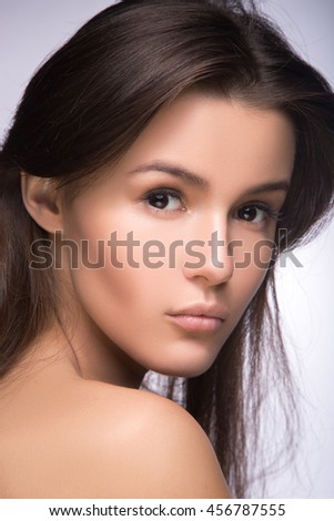 Closeup portrait of beautiful girl with clear healthy skin. Looking at the camera over shoulder. perfect fashion model studio photo