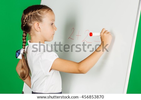 portrait of school girl in a school uniform near whiteboard with red marker. Learning, idea and school concept. Image on green background.