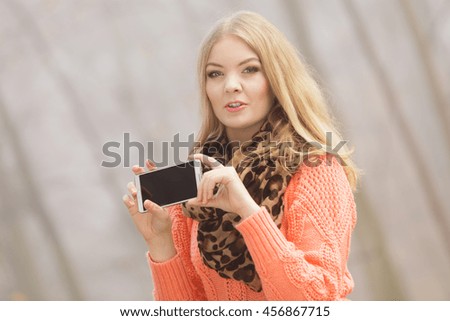 Lovely fashion woman in fall autumn park taking selfie self photo picture. Pretty cute young girl in sweater pullover photographing.