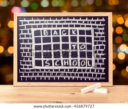 humorous concept of hate school as prison with text back to school is written in chalkboard, chalks on wooden table over blur background, close up