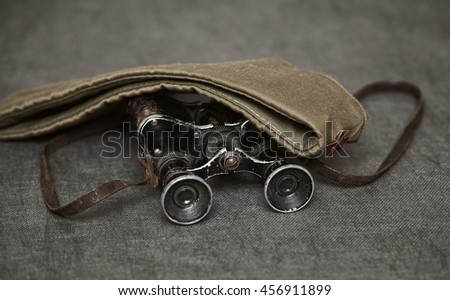 Military binoculars and a cap on a dark background, vintage style