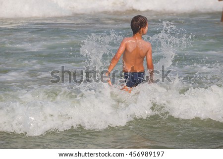 Picture of exciting boy running on beach beside waves. image of kid in evening sunlights on seaside background