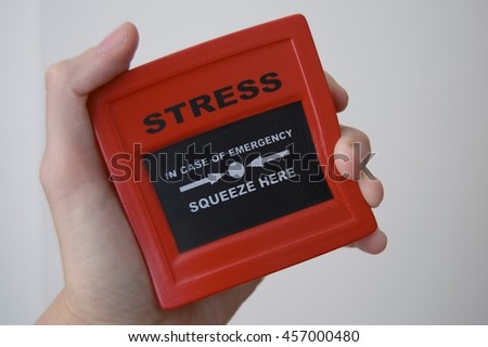 Somebody squeezing an iconic emergency stress cube or ball due to increasing pressure about jobs work money mortgage and everyday problems and a tough day on british transport.