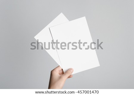 A5 Flyer / Invitation Mock-Up - Male hands holding blank flyers on a gray background. Royalty-Free Stock Photo #457001470