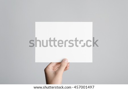 A5 Flyer / Invitation Mock-Up - Male hands holding a blank flyer on a gray background. Royalty-Free Stock Photo #457001497