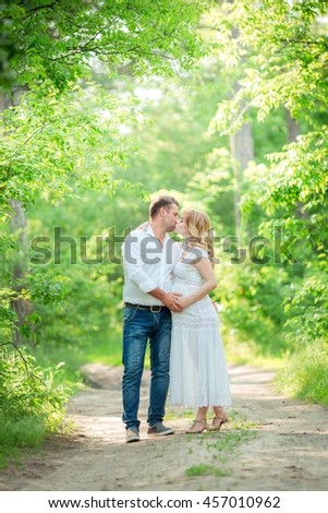 Beautiful pregnant woman with her husband in green garden