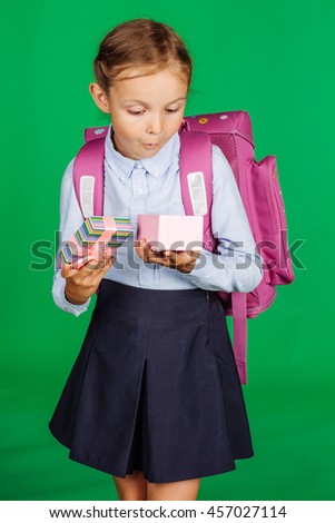 portrait of school girl in a school uniform with gift box. Learning, idea and school concept. Image on green background.