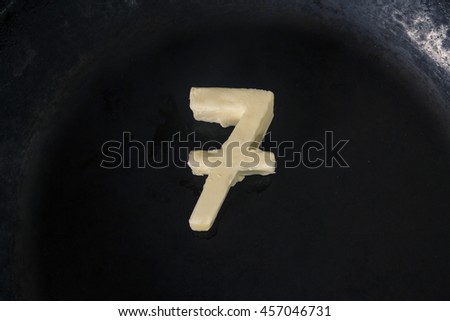 Butter in shape of number 7 on hot pan - Close up top view 
