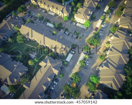 Aerial view of apartment garage with full of covered parking, cars and green trees of multi-floor residential building at sunset in US. Urban infrastructure and transportation concept. Vintage filter.