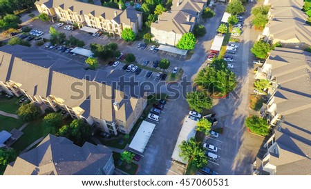 Aerial view of apartment garage with full of covered parking, cars and green trees of multi-floor residential building at sunset in US. Urban infrastructure and transportation concept. Panorama view.