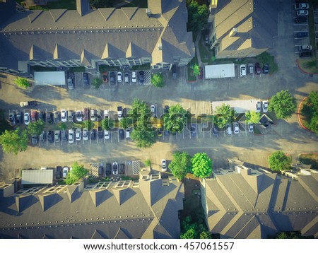 Aerial view of apartment garage with full of covered parking, cars and green trees of multi-floor residential building at sunset in US. Urban infrastructure and transportation concept. Vintage filter.