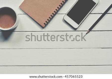 Office supplies, notebook, coffee, smartphone and pencil on white wood desk 