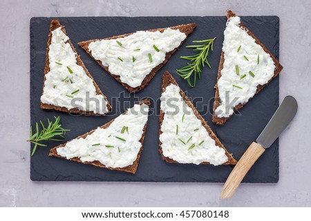 Pumpernickel bread with feta, cream cheese, rosemary, lemon and garlic dip, on slate board, top view, horizontal Royalty-Free Stock Photo #457080148