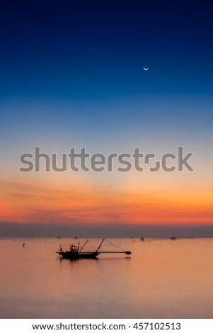 A boat is floating under colorful sky at sunset time reflection on sea location at east of Thailand