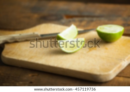 Fresh cut limes on wooden cutting board background with blur applied to image.
