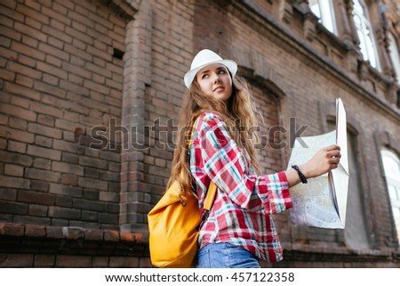 Female tourist with map visiting city and looking around